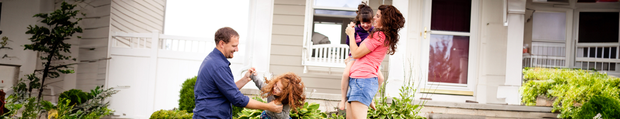 Parents playing with their two daughters outside of their home