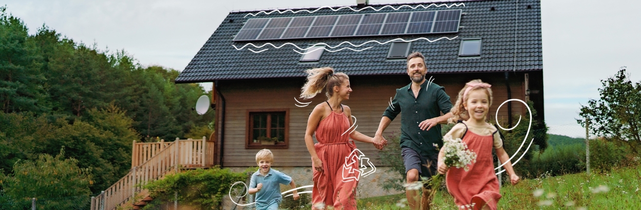a mom, dad, and their two children run up a hill in front of a house with solar panels